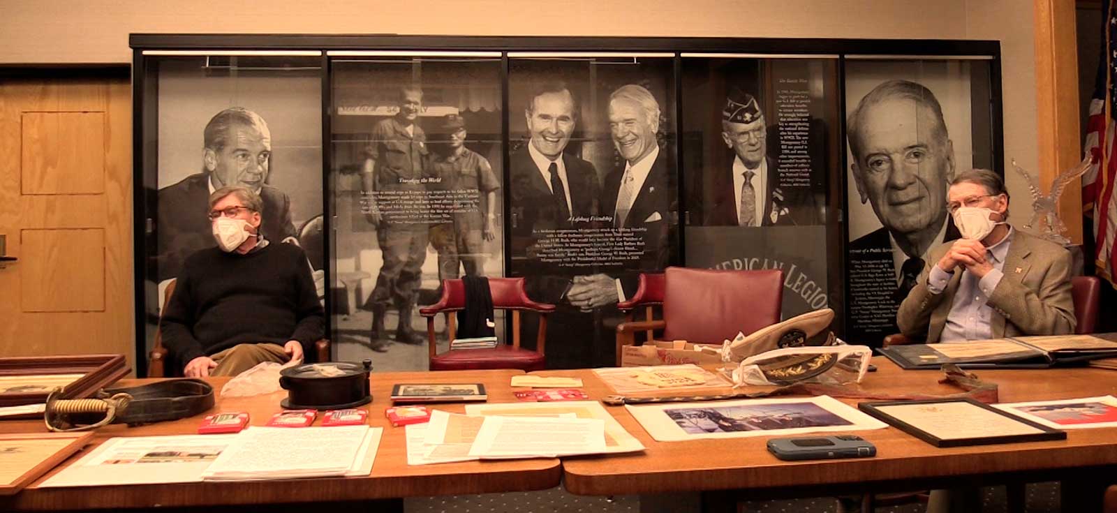 The Wallace brothers sit at a table on which is spread materials from their donated collection.