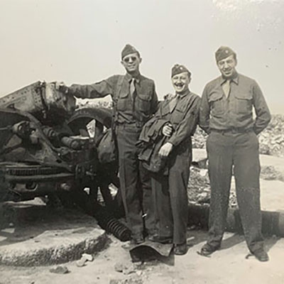 James Franklin 'Frank' Buchanan and two unidentified men in front of World War II machinery.