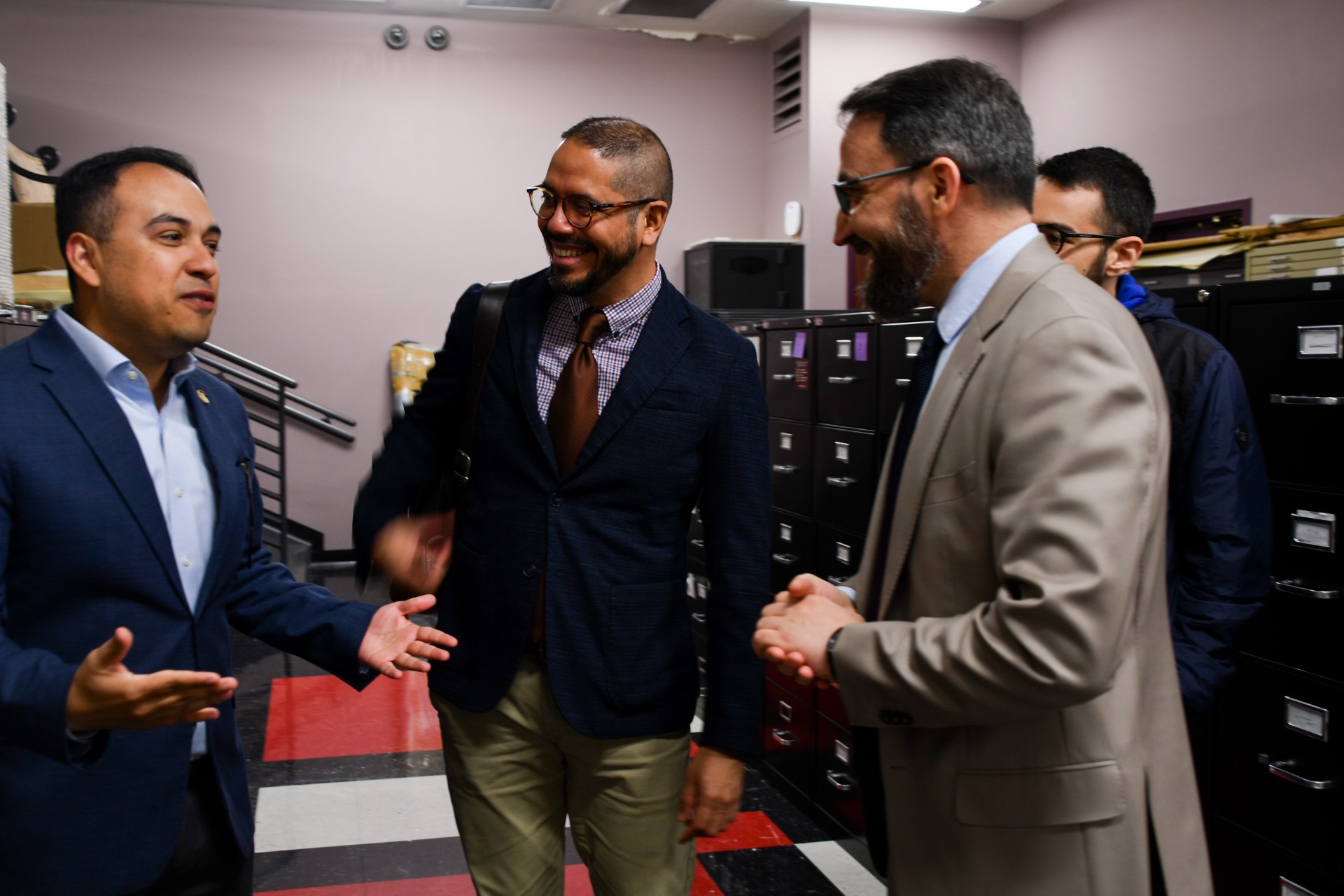 Three men stand together, talking and laughing in conversation at Mississippi State University Libraries.