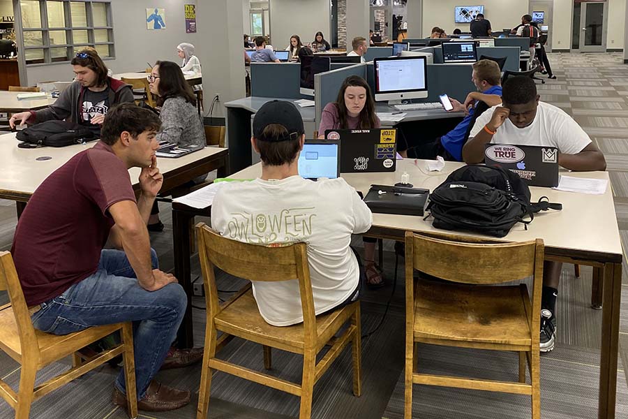 Students around a computer work on a group project in the DMC