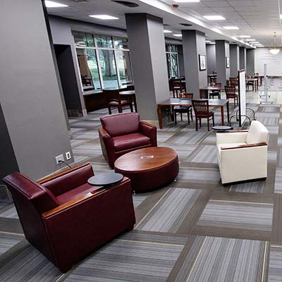 Chairs and tables in front of a row of picture windows.