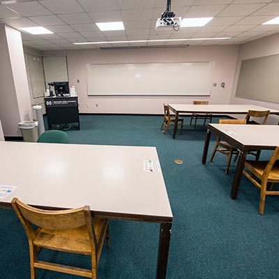 Work tables in front of a presentation screen and podium.