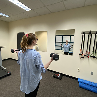A young woman uses weights to work out in the Learn and Burn Room.