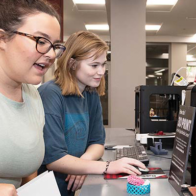 Students observe a 3D printer at work.