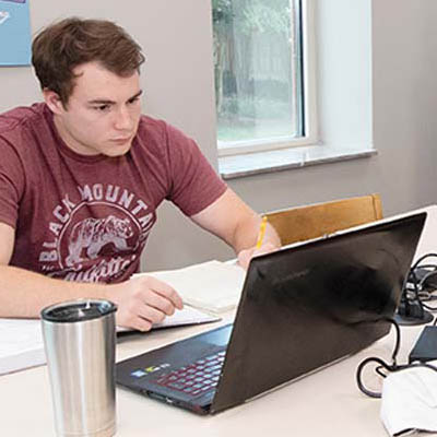 A student works at a table on a laptop computer.
